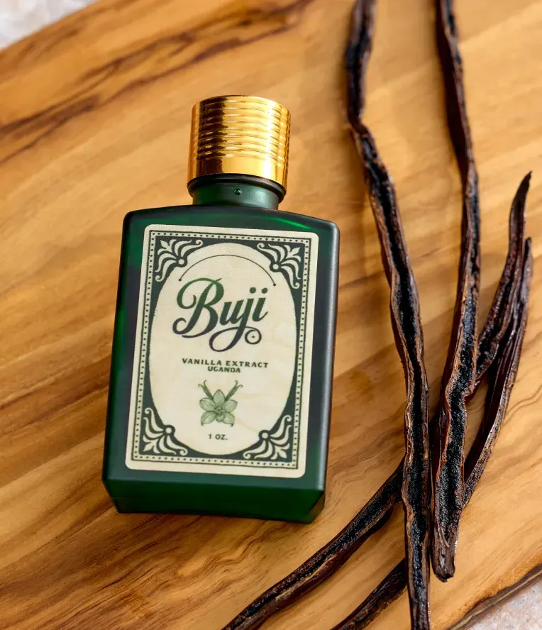 A bottle of Buji vanilla extract beside vanilla pods